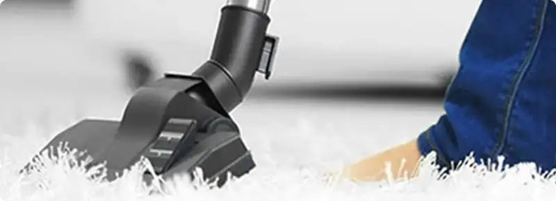 Close-up of a professional vacuuming a white carpet in Avon.