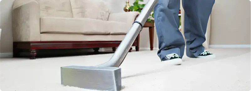 Carpet cleaning technician using a hot-water extraction wand on a light-colored carpet in a living room, Indianapolis, IN.