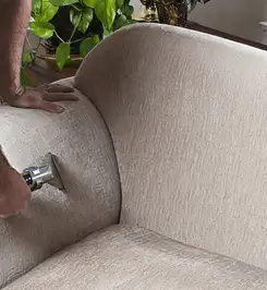 Professional upholstery cleaner deep-cleaning a fabric sofa with a handheld extraction tool and hose Indianapolis, IN.